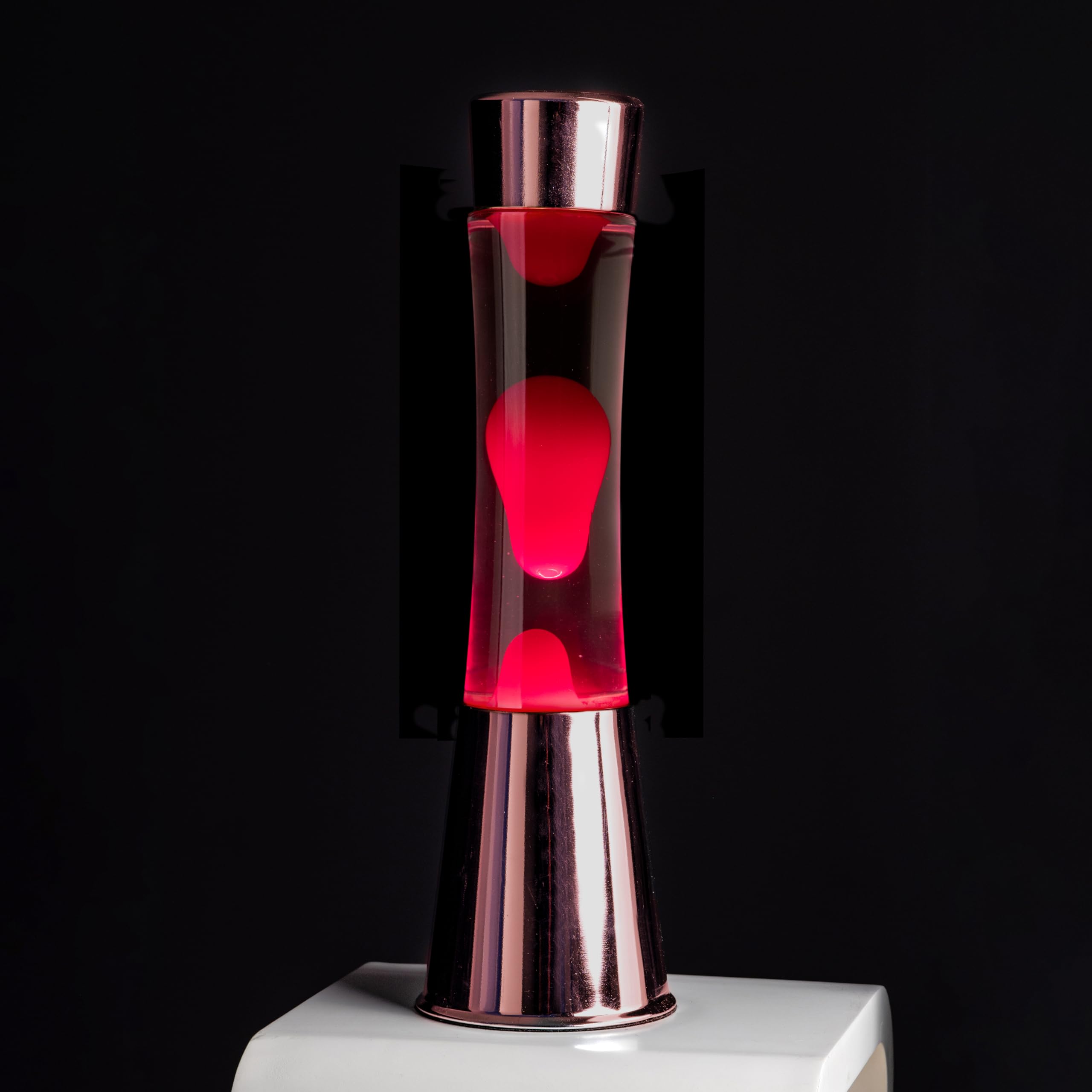 FISURA - Lavalampe rosa. Roségoldfarbener Chromsockel, transparente Flüssigkeit und rosa Lava. Lavalampe mit Ersatzbirne. Maße: 11 x 11 x 39,5 Zentimeter.
